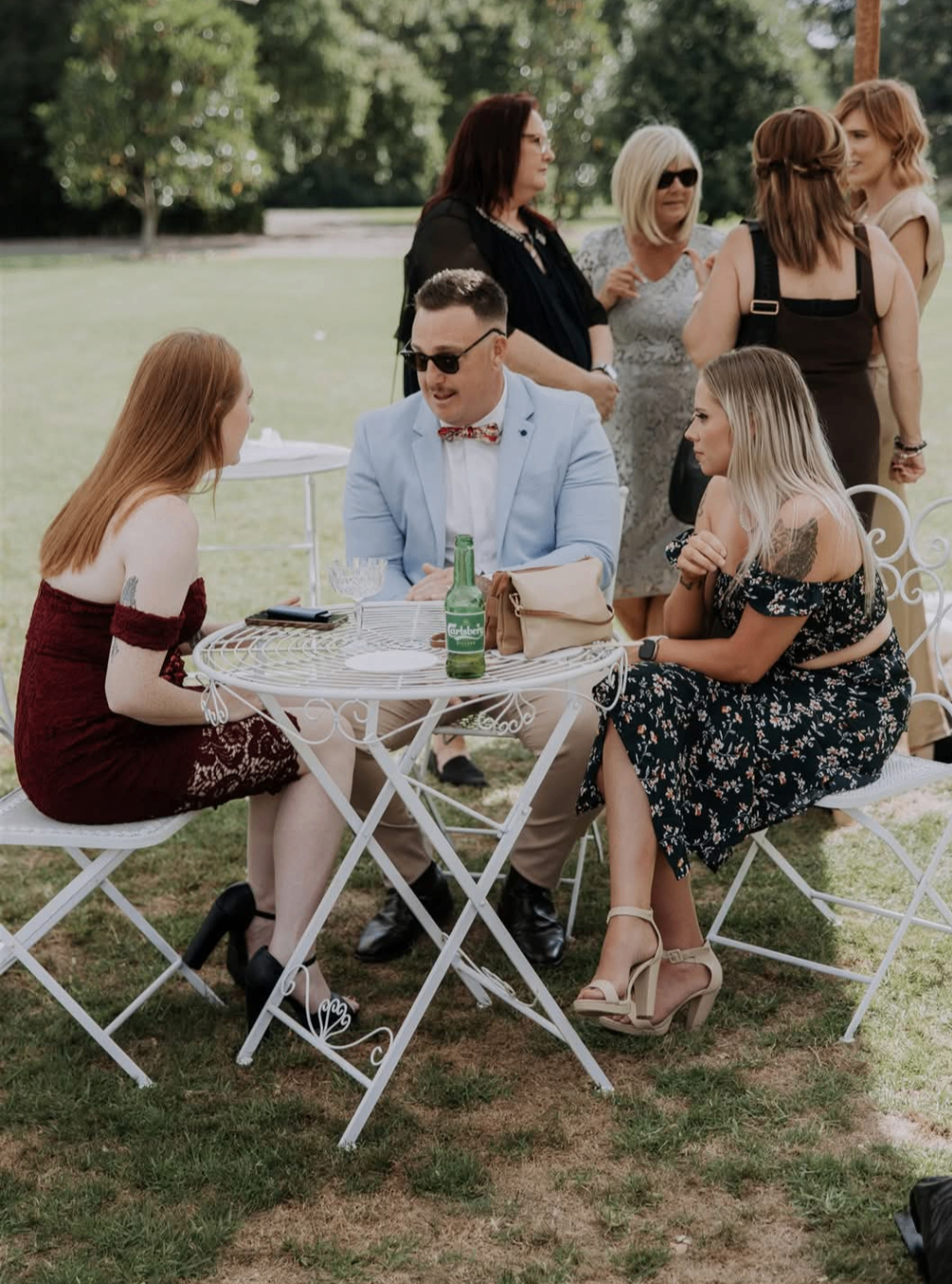 Wedding guests seated around white bistro furniture during the reception