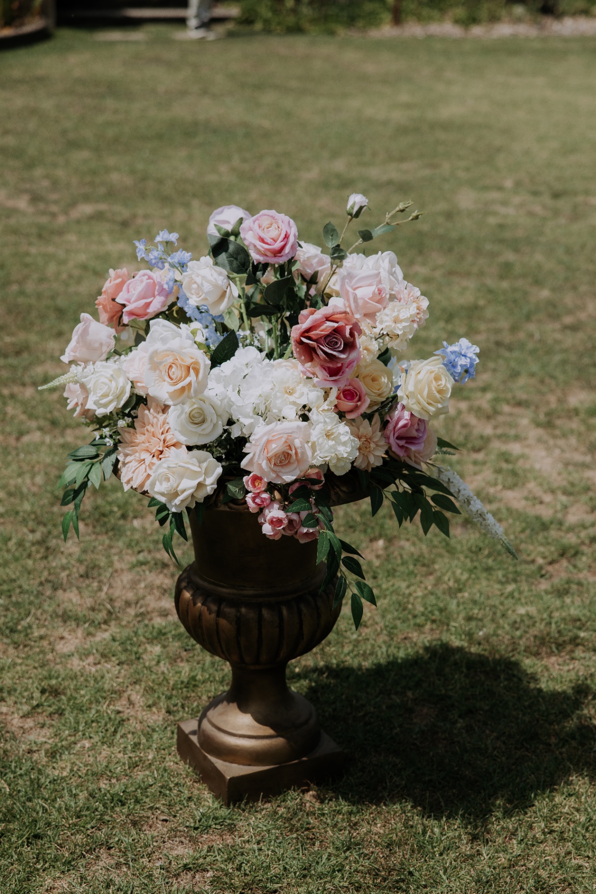 Bronze urn arrangement with soft blush, cream and blue florals