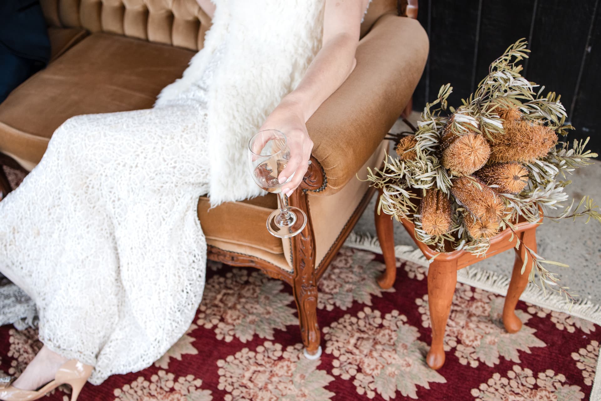 Bride seated beside a floral arrangement on a vintage side table at The Stables Port Stephens