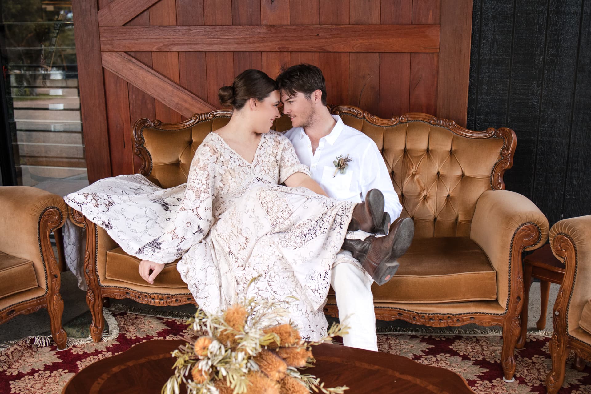 Newlyweds seated together on a caramel vintage lounge at The Stables Port Stephens